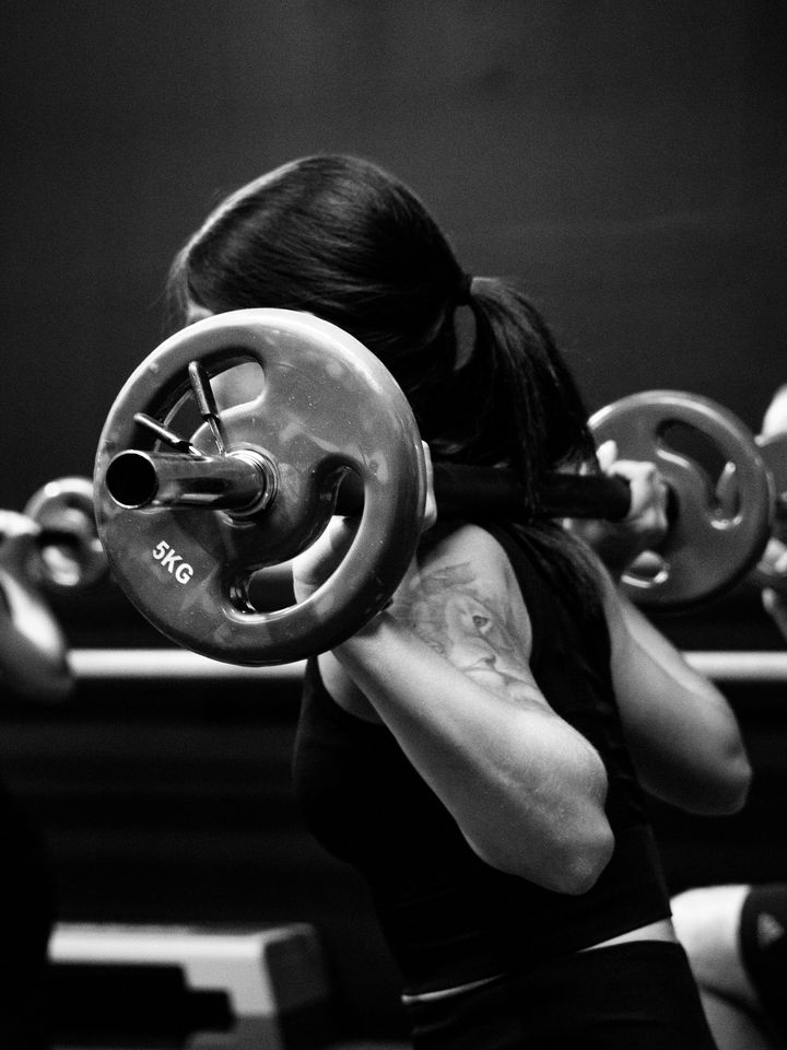 People squatting with barbells in a group fitness class