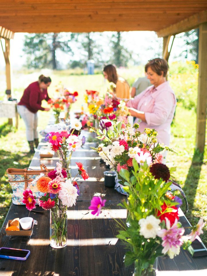 Women arranging flowers at a long outdoor table